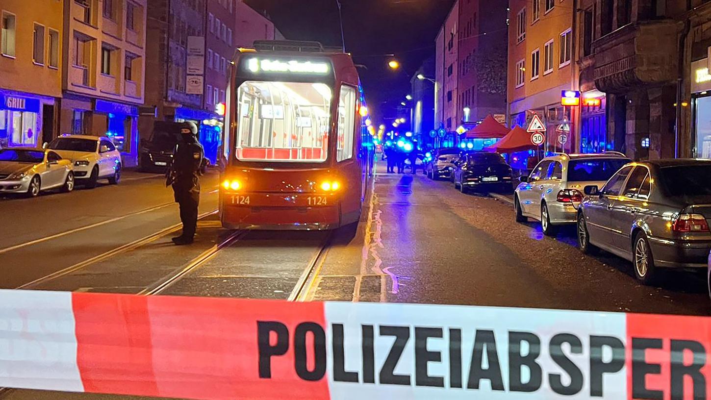 Am Tatort an der Landgrabenstraße steht ein Polizist mit einer Maschinenpistole hinter der Polizeiabsperrung.