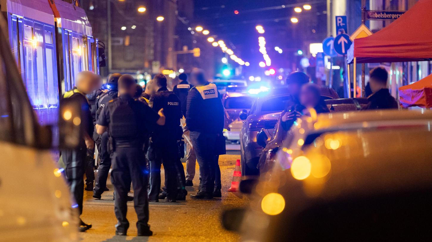 Polizisten stehen neben einer Straßenbahn in der Nähe eines Tatorts einer Schießerei. Bei Schüssen in der Nürnberger Südstadt ist am 24. Oktober ein Mann ums Leben gekommen, ein weiterer wurde schwer verletzt.