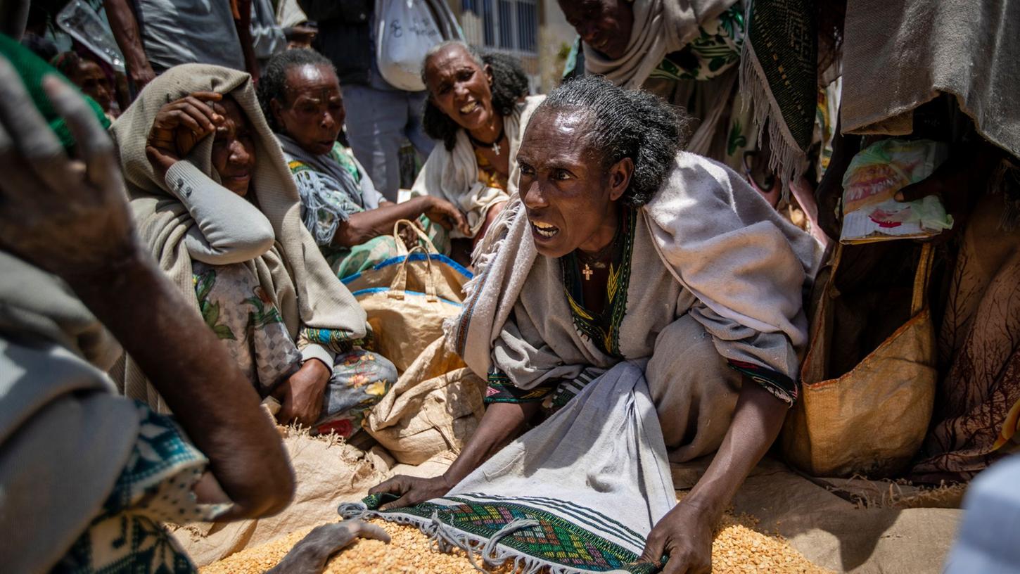 Eine äthiopische Frau streitet mit anderen über die Verteilung von gelben Spalterbsen, nachdem diese von einer Hilfsorganisation in der Region Tigray verteilt worden waren. Eine äthiopische Frau streitet mit anderen über die Verteilung von gelben Spalterbsen, nachdem diese von einer Hilfsorganisation in der Region Tigray verteilt worden waren.