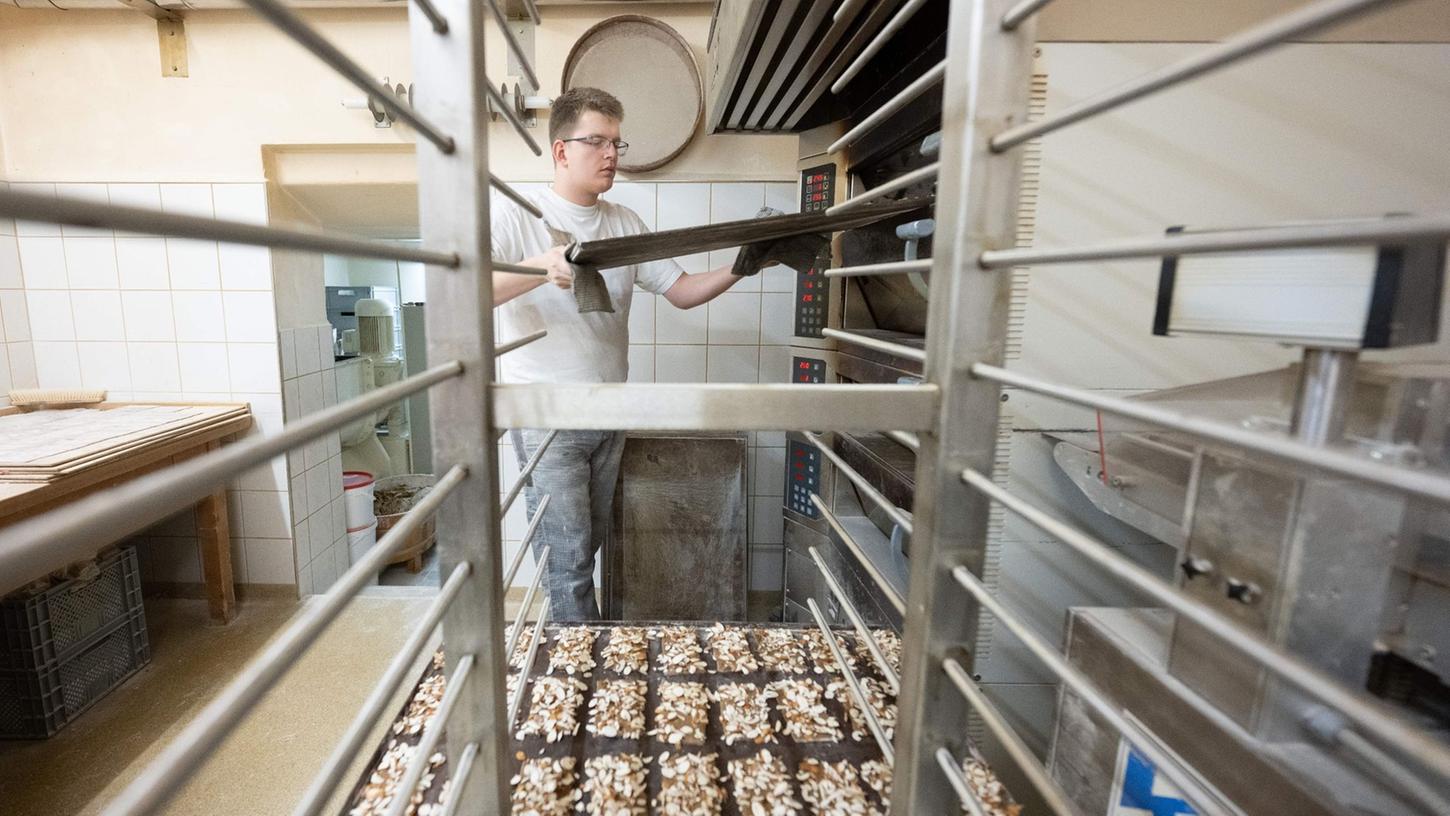 Der Pfefferküchler-Meister Martin Kotzsch nimmt in der Backstube der Pfefferküchlerei Hermann Löschner ein Backblech mit Pfefferkuchen aus dem Ofen.