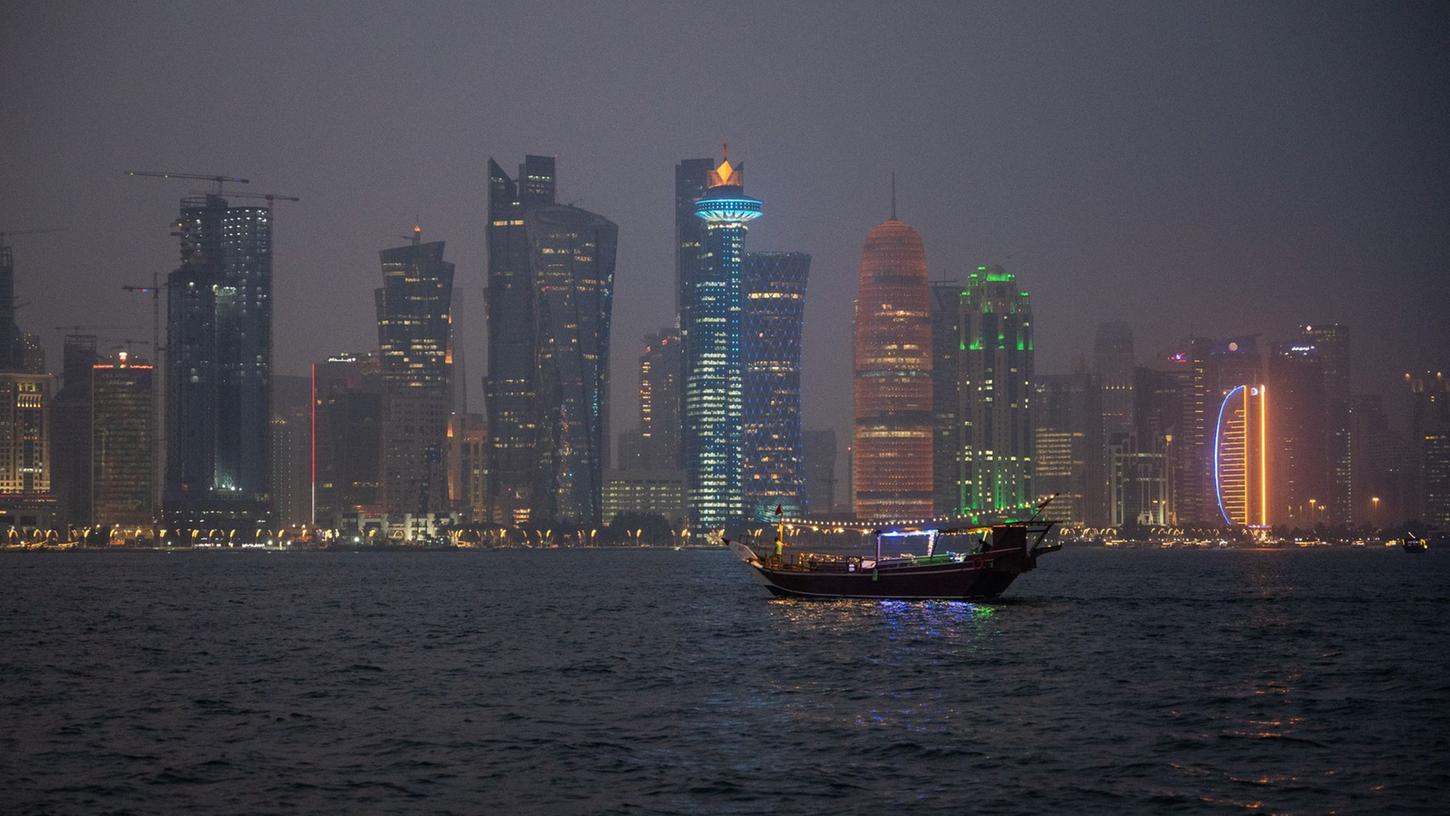 Ein traditionelles Holzschiff, Dhow genannt, fährt am Abend in der Bucht vor der katarischen Hauptstadt Doha.