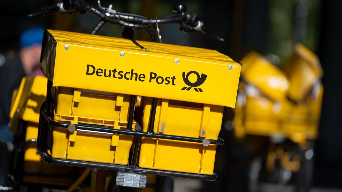 Ein Fahrrad von der Deutschen Post steht an einer Straße.