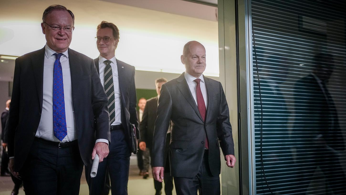 Bundeskanzler Olaf Scholz (r, SPD), Stephan Weil (l, SPD), Ministerpräsident von Niedersachsen, und Hendrik Wüst (CDU), Ministerpräsident von Nordrhein-Westfalen, kommen nach der Ministerpräsidentenkonferenz zur Pressekonferenz. 