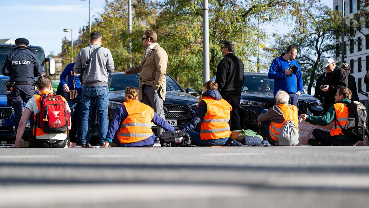 Klimaaktivisten haben sich am Karlsplatz in der Münchner Innenstadt auf die Fahrbahn geklebt und blockieren die Straße.