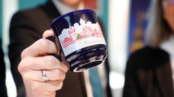 Aus der Christkindlesmarkt-Tasse aus 2022, die sich in der Form von denen der Vorjahre wieder unterscheidet, kann beispielsweise an der Fleischbrücke die "größte Feuerzangenbowle der Welt" genossen werden. Dort verzaubert das Licht "der hellen Flammen über dem eigens angefertigtem Kessel" den Platz in ein romantisches Örtchen.