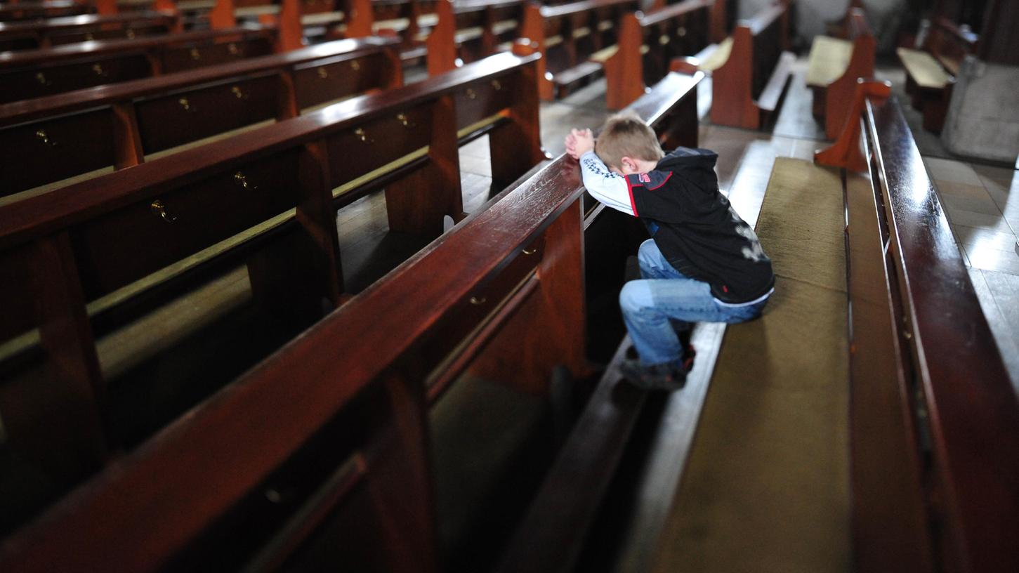 Ein Junge kniet in einer Kirchenbank: Auch Minderjährige sind Opfer des Pfarrvikars geworden, der sie in seine Fürther Wohnung gelockt hatte.
