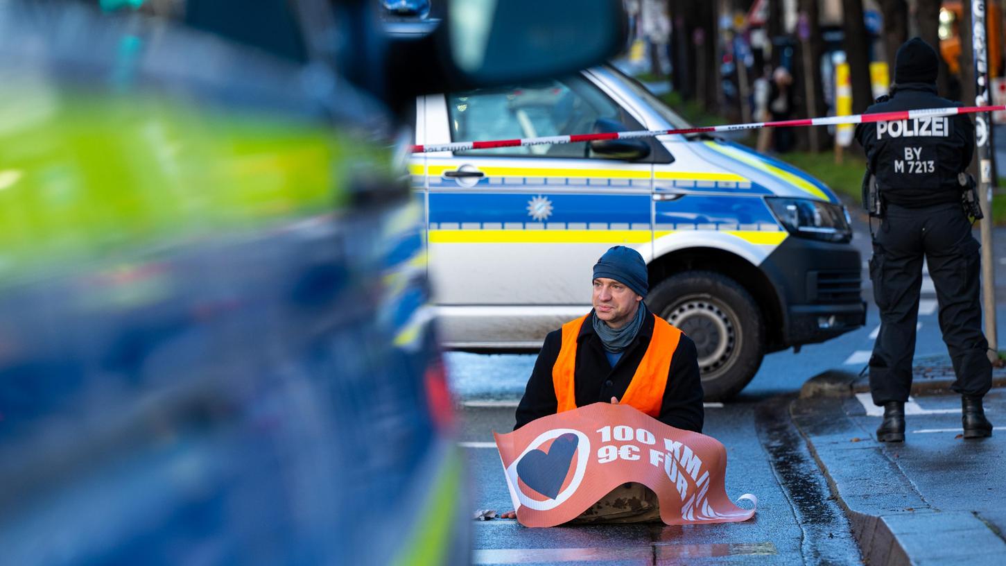 Ein Klimaaktivist der Umweltschutzbewegung «Letzte Generation» sitzt auf der Prinzregentenstraße in München und blockiert den Verkehr. 
