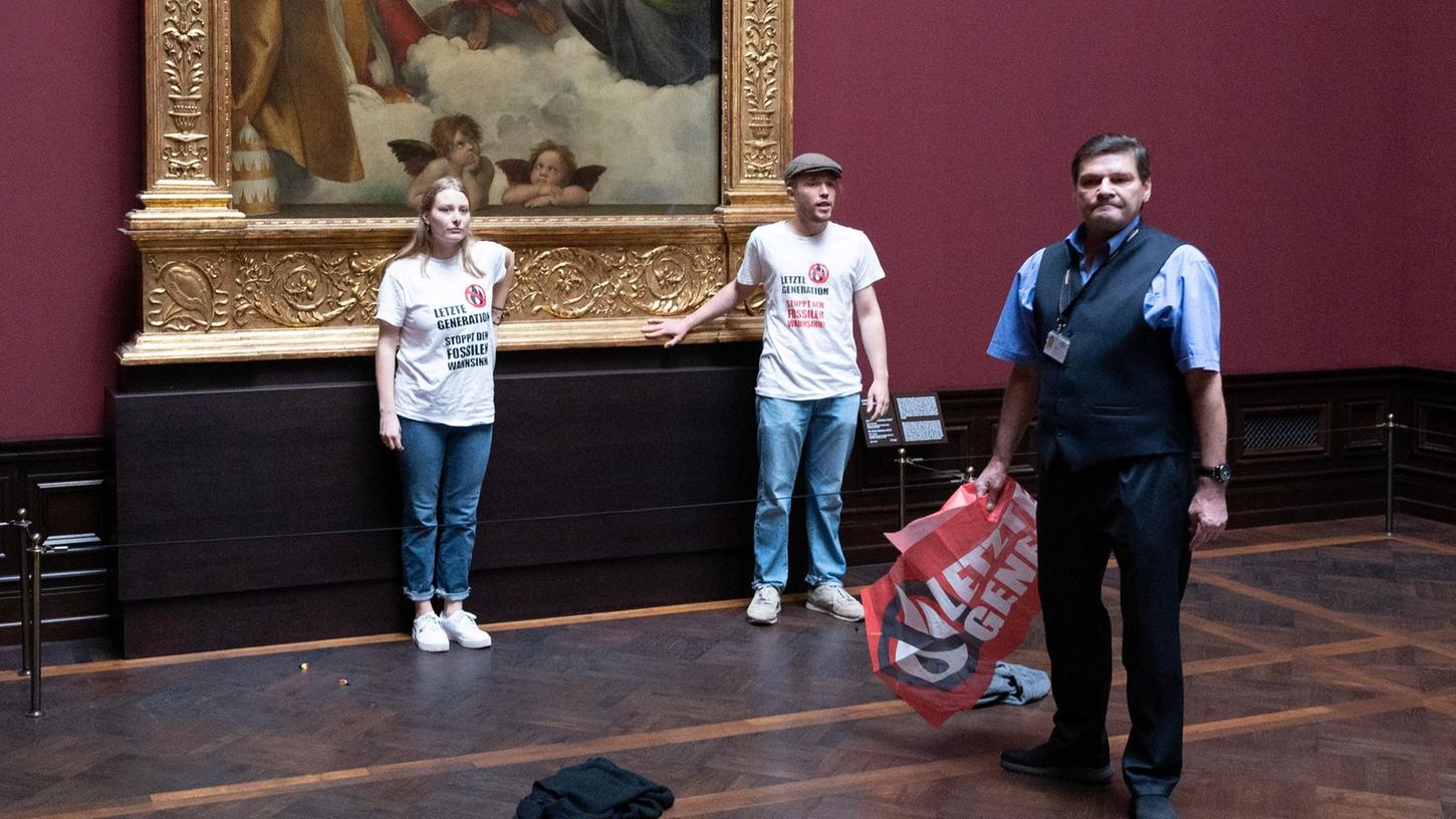 Zwei Umweltaktivisten der Gruppe "Letzte Generation" stehen in der Gemäldegalerie Alte Meister am Gemälde "Sixtinische Madonna" von Raffael.