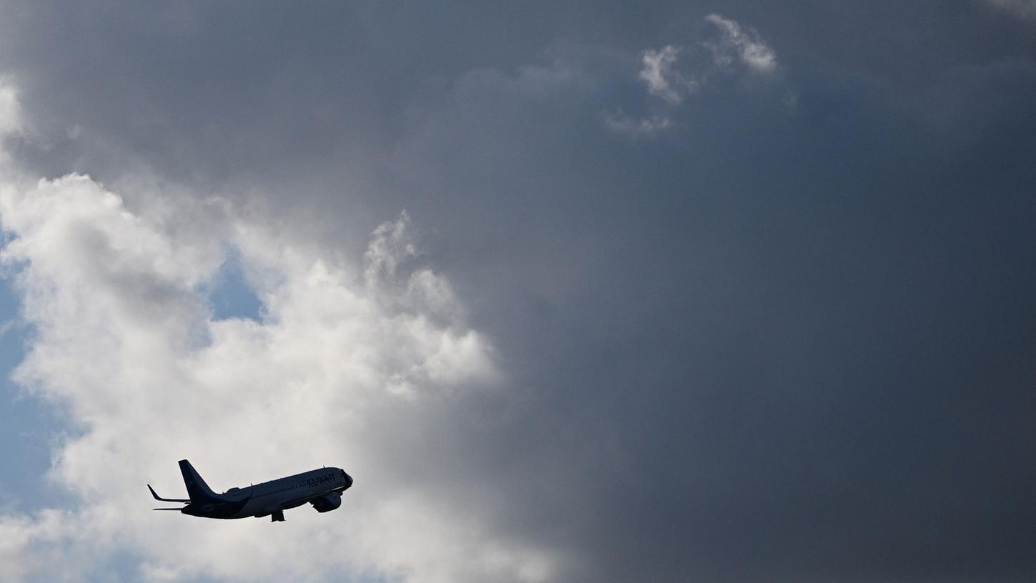 Ein Flugzeug fliegt nach seinem Sart am Flughafen München auf dunkle Wolke zu.