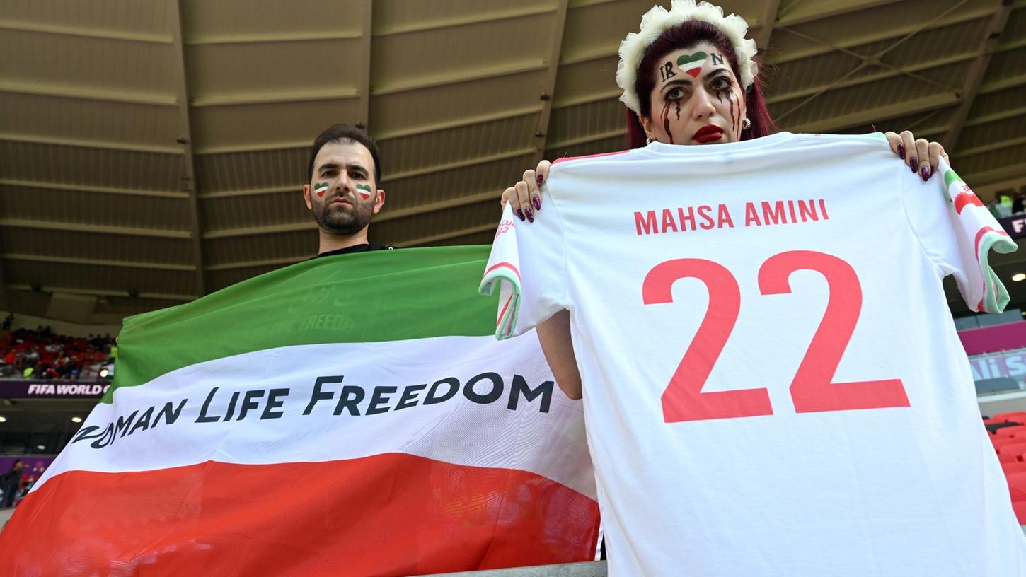 Iraner protestieren vor dem Spiel und halten eine Flagge mit der Aufschrift "Women Life Freedom".