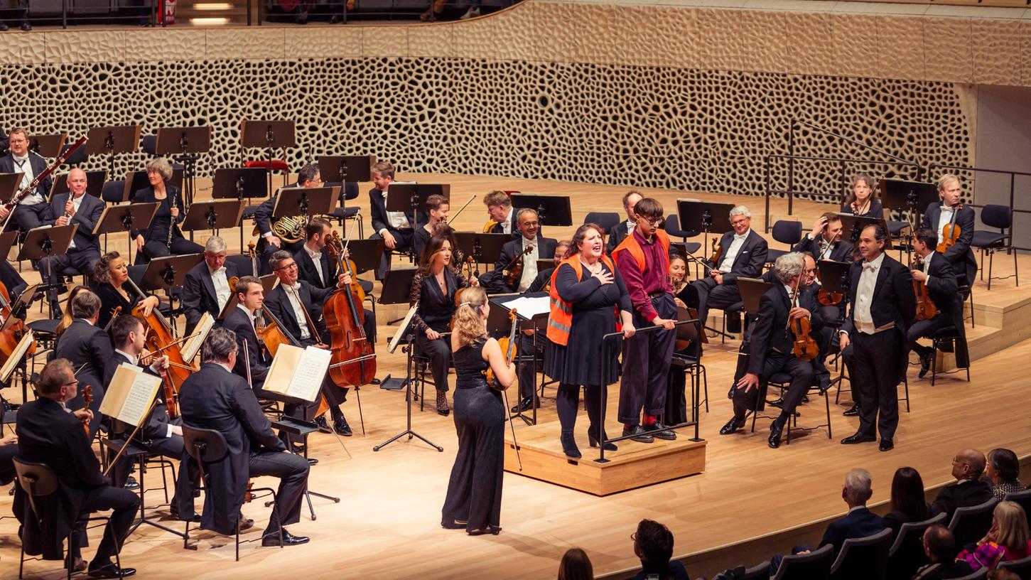 Zwei Aktivisten stehen auf der Bühe der Elbphilharmonie. Kurz vor Beginn eines Konzerts in der Elbphilharmonie haben Klimaaktivisten der "Letzten Generation" sich am Mittwochabend an einem Dirigentenpult festgeklebt.