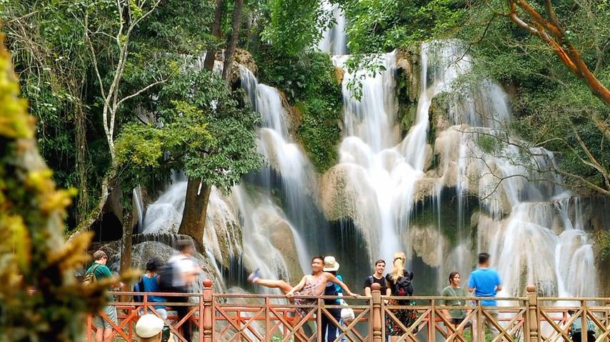 Touristen laufen über eine Brücke vor dem Haupt-Wasserfall von Suang Si. In den vielen Kaskaden darunter kann man prima baden. Die spannende Reportage zu dieser Bildergalerie lesen Sie auf unserem Premiumportal nn.de