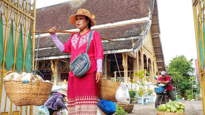 Gelassen geht es zu in Laos - wie in früheren Jahrhunderten trägt diese Frau ihre Ware in Körben auf den Morgenmarkt in Luang Prabang.