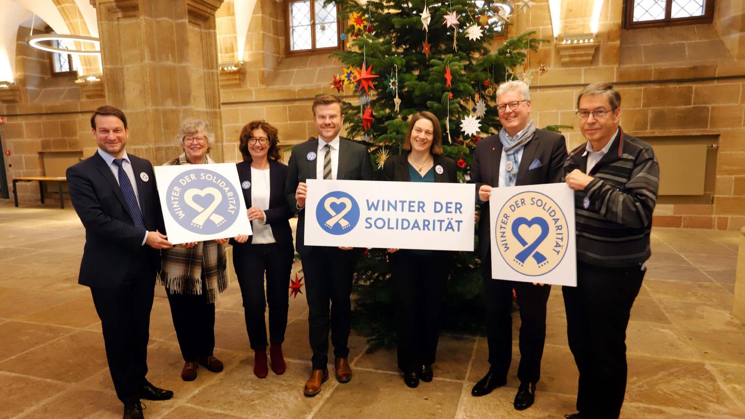 Auftakt zum "Winter der Solidarität" in der Ehrenhalle des Nürnberger Rathauses (v.li.): Caritas-Direktor Michael Schwarz, Antje Rempe vom Partnerschaftsverein Nürnberg-Charkiw, Annekathrin Fries, Leiterin des Amts für Kultur und Freizeit, OB Marcus König, Sozialreferentin Elisabeth Ries, Sparkassenvorstand Matthias Everding und vnp-Redakteur Wolfgang Heilig-Achneck als Vertreter von "Freude für alle" rufen zum Zusammenhalt auf.