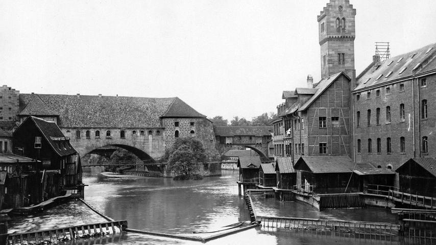So sahen die im Krieg zerstörten Nägeleinsmühlen um die Jahrhundertwende aus. Dahinter überspannt der Kettensteg unterhalb des Westtorzwingers die Pegnitz.