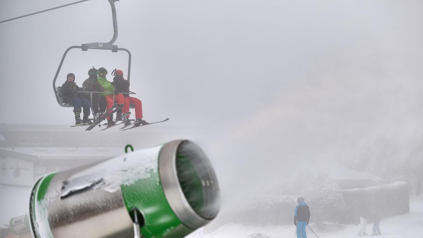 Wintersportler gondeln über einer künstlich beschneiten Piste an der Remmerswiese nach oben.