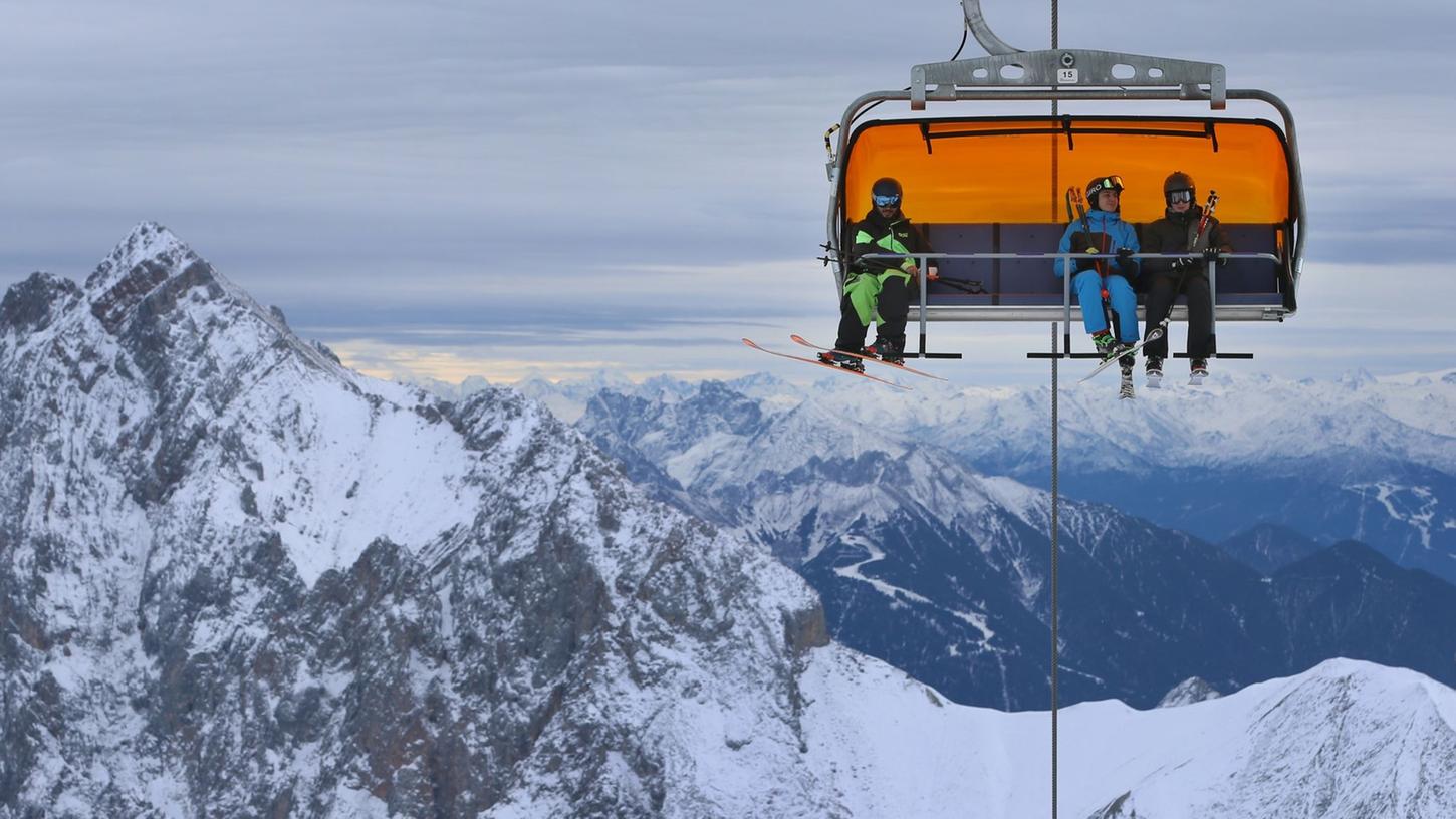 Wintersportler sitzen auf der Zugspitze in einem Sessellift.