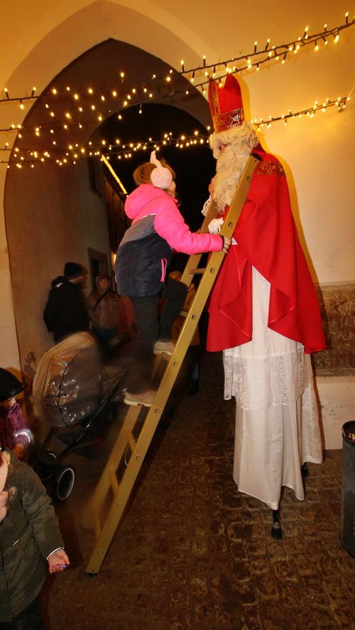 Hoch hinauf zum Nikolaus auf Stelzen klettern die Kinder vor dem Schlossinnenhof.