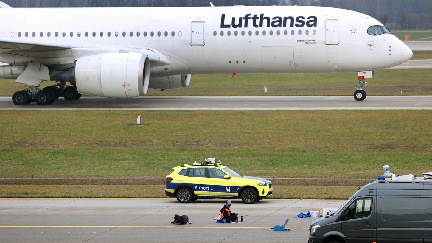 Ein Klimaaktivist sitzt mit angeklebter Hand auf dem Start-und Landebahn am Airport Franz-Josef-Strauß in München. Ein Klimaaktivist sitzt mit angeklebter Hand auf dem Start-und Landebahn am Airport Franz-Josef-Strauß in München.