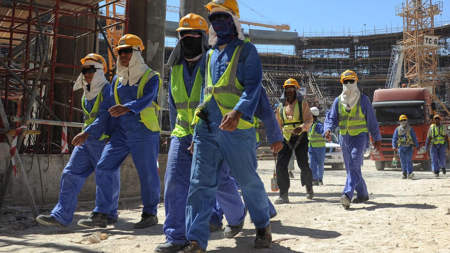 Ausländische Bauarbeiter verlassen eine Baustelle in Doha.