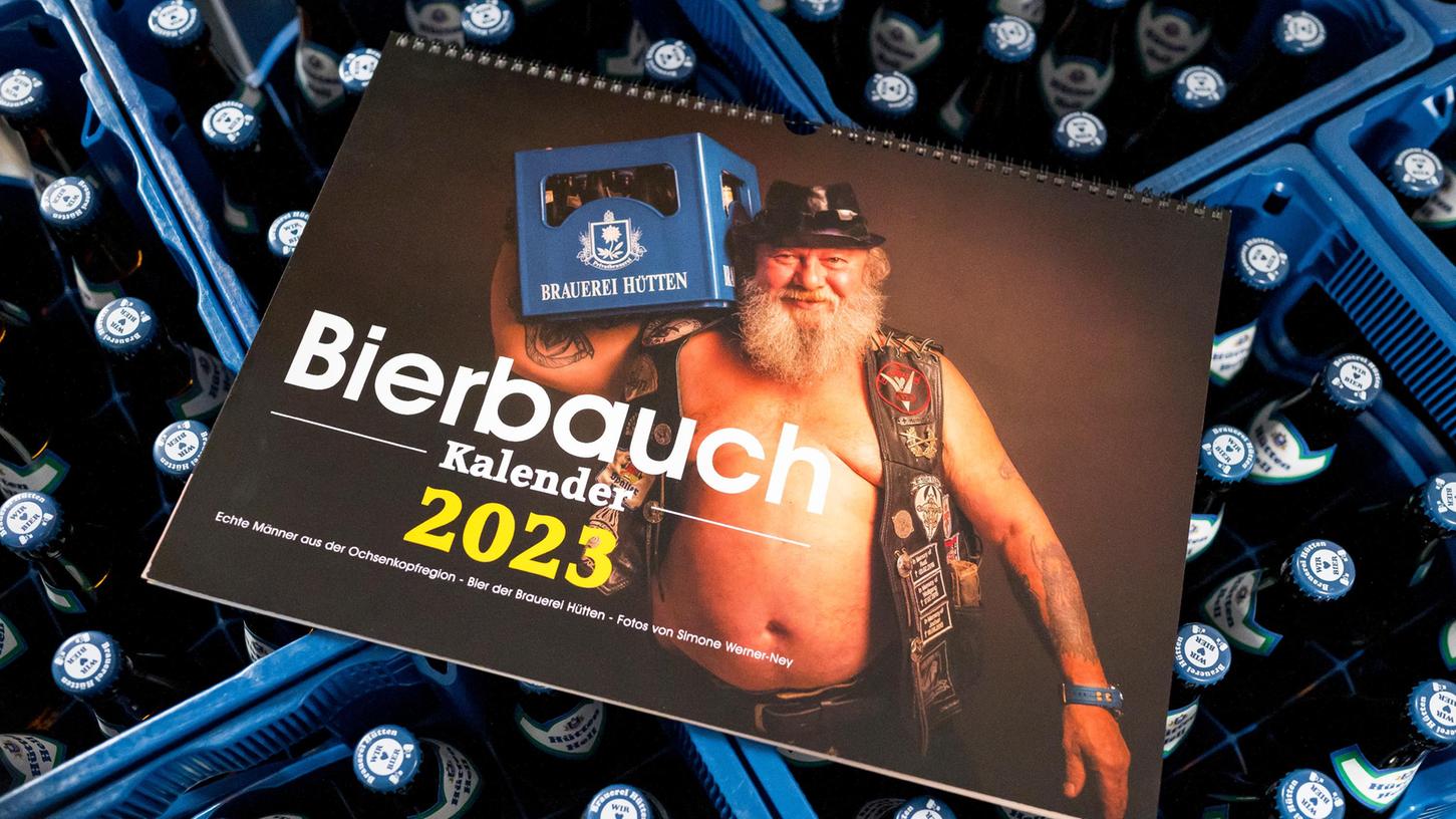 Der "Bierbauchkalender 2023" liegt auf Bierkästen. Eine Fotografin hatte die Idee für den Bierbauchkalender, dieser war zunächst nur als Aprilscherz gedacht. Gemeinsam haben sie und ein Braumeister von der Brauerei Hütten den Bierbauchkalender jetzt herausgebracht.
