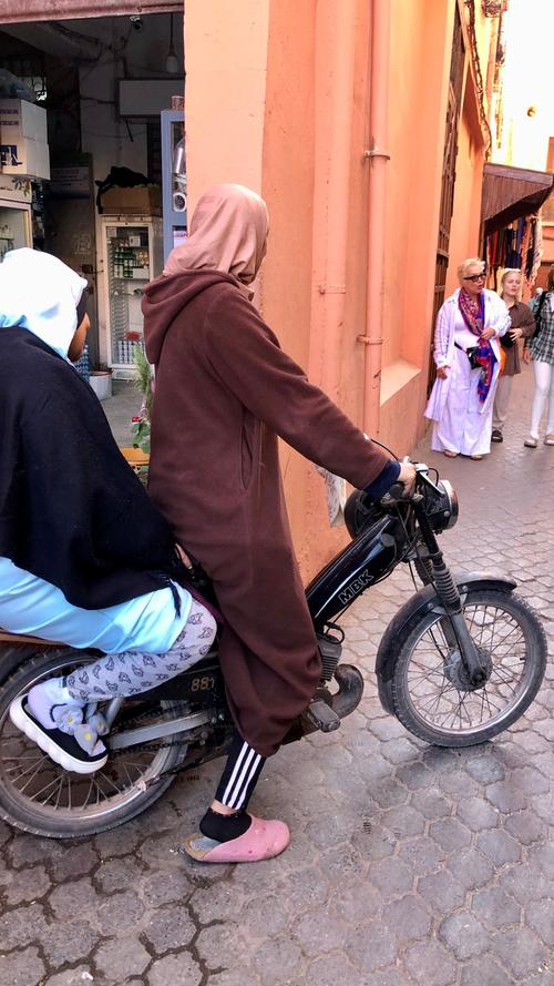 Marrakesch wird in Marokko auch die "City of Bikes" genannt. Nirgendwo sonst im Königreich sollen vor allem so viele Frauen auf den kleinen Motorrädern, Mopeds oder Rollern unterwegs sein. Die motorisierten Zweiräder sind jedenfalls fester Bestandteil des Stadtbildes und werden von groß und klein, alt und jung sowie von Frauen und Männern durch die kleinen Gassen der Stadt gesteuert. Nicht selten waghalsig mit hohem Tempo und knapp an den anderen Verkehrsteilnehmern und Fußgängern vorbei.