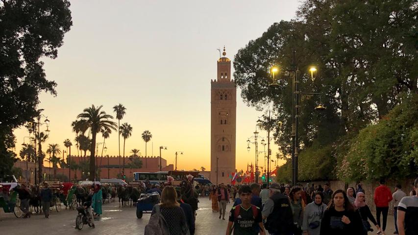 Das Minarett der berühmten Koutoubia Moschee erleuchtet im Abendrot und ist vom Djemaa el Fna gut zu sehen. Pünktlich zum Sonnenuntergang ertönt der Ruf des Muezzin und hallt über den Platz der Gaukler.