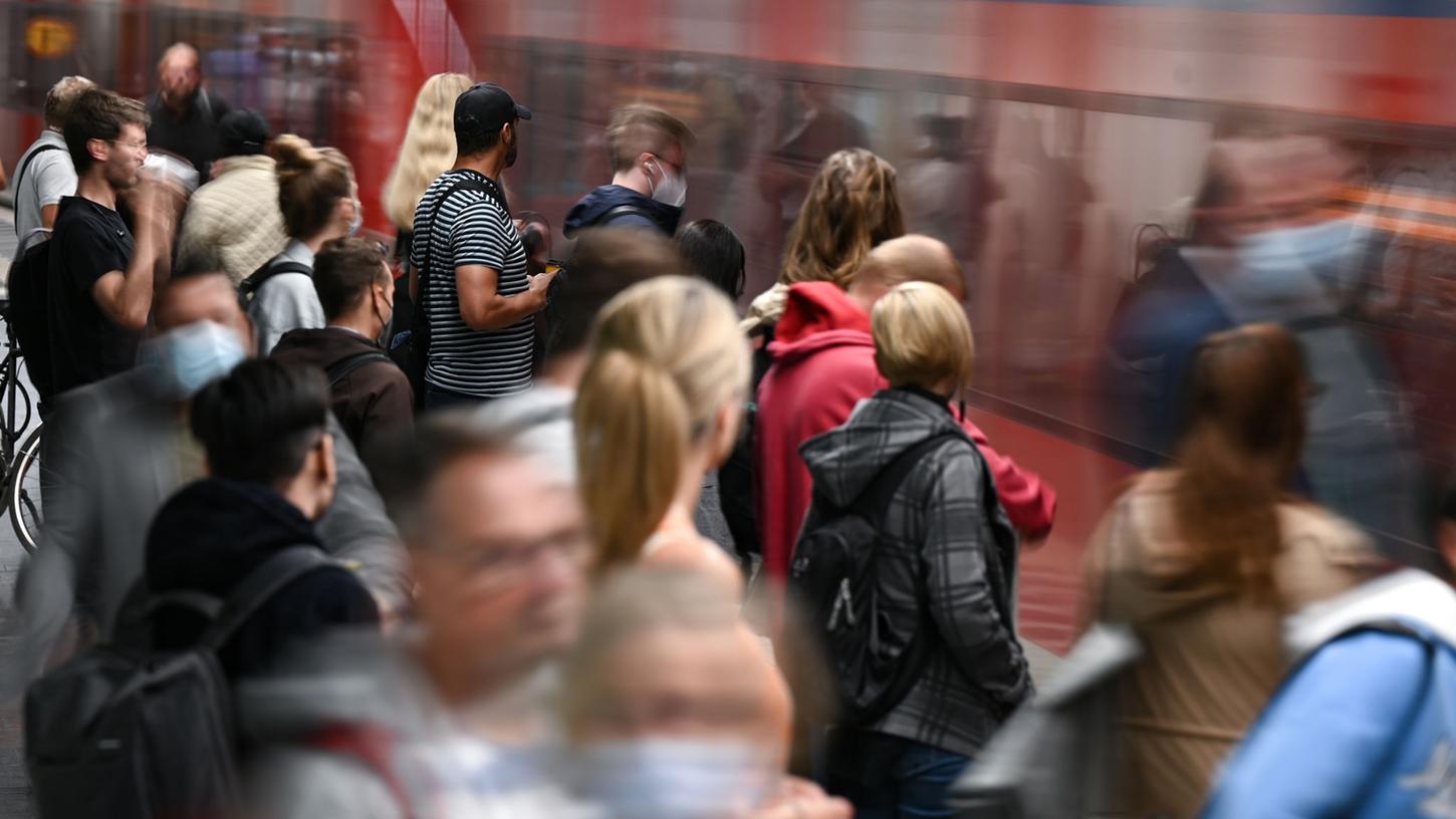 Fahrgäste warten an einem Gleis im Tiefbahnhof des Frankfurter Hauptbahnhofs, während eine S-Bahn einfährt.