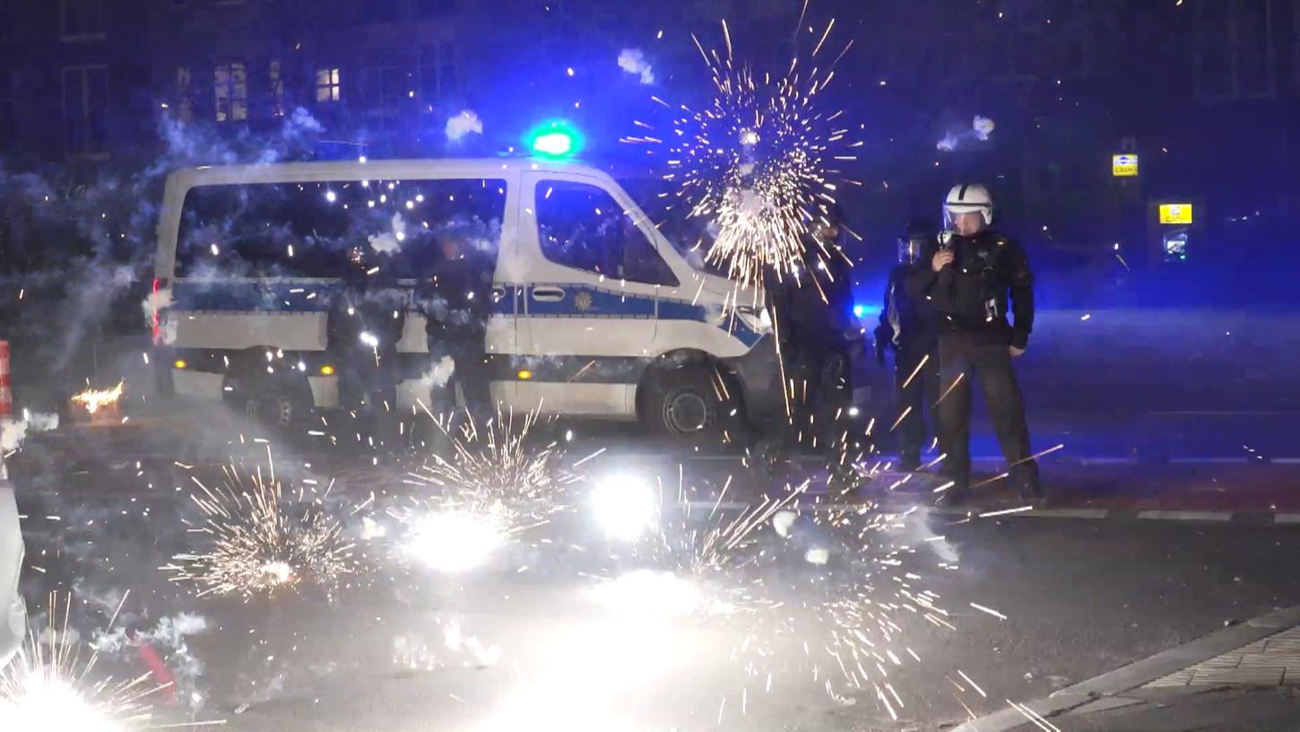 Polizeibeamte in Berlin hinter explodierendem Feuerwerk. Nach Angriffen auf Einsatzkräfte in der Silvesternacht hat die Diskussion um Konsequenzen begonnen. 
