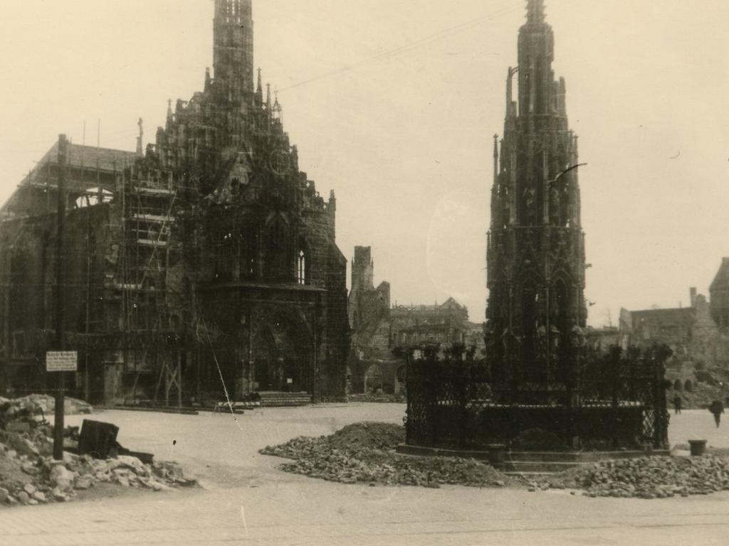 Dank einer - auf dieser Aufnahme von 1945 schon entfernten - Ummantelung aus Beton widerstand der Schöne Brunnen dem Bombenhagel. Die Frauenkirche und die Häuser am Hauptmarkt hatten weniger Glück. 