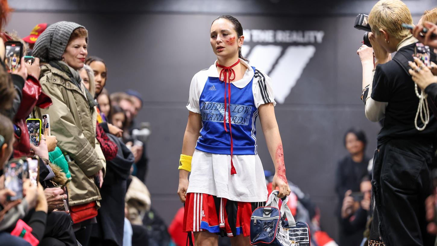 Eine Aktivistin geht bei einer als Adidas-Show getarnten Performance im Rahmen der Berliner Fashion Week über den Laufsteg Eine Aktivistin geht bei einer als Adidas-Show getarnten Performance im Rahmen der Berliner Fashion Week über den Laufsteg