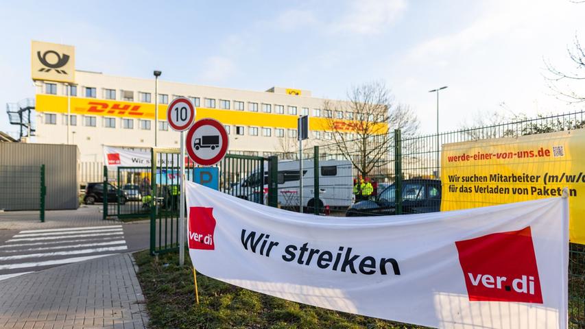 Ein Banner mit der Aufschrift "Wir streiken" hängt vor einem Gebäude des Paketdienstleisters DHL in Lahn.