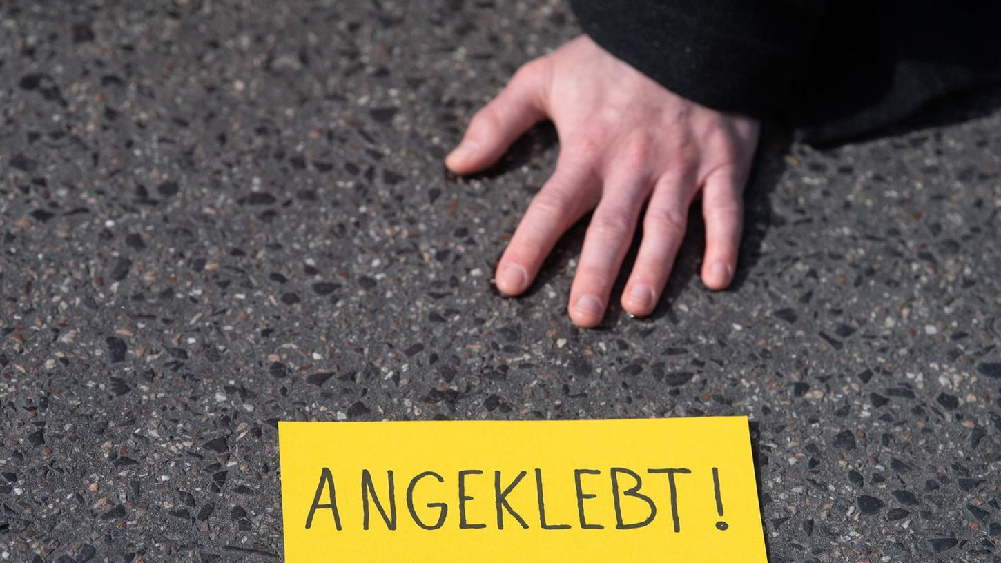 Ein Demonstrant hat sich während eines Protests der Gruppe "Letzte Generation" auf einer Straße festgeklebt. Ein Demonstrant hat sich während eines Protests der Gruppe "Letzte Generation" auf einer Straße festgeklebt.