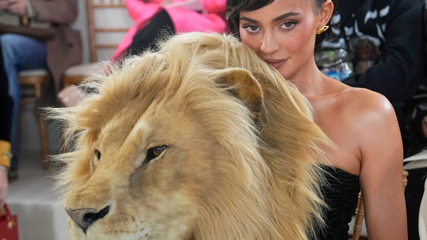 Kylie Jenner hinter einem täuschend echt aussehenden Löwenkopf.