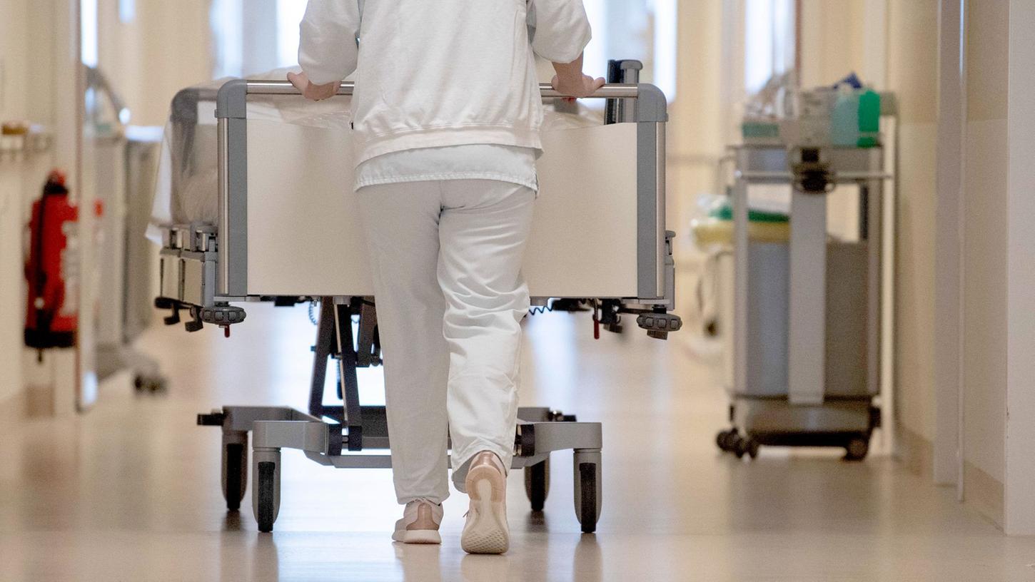 Eine Krankenpflegerin schiebt ein Krankenbett durch einen Flur. Krankenhäuser gehören zu den Bereichen, in denen sich der Fachkräftemangel laut Studie weiter verschärfen wird.