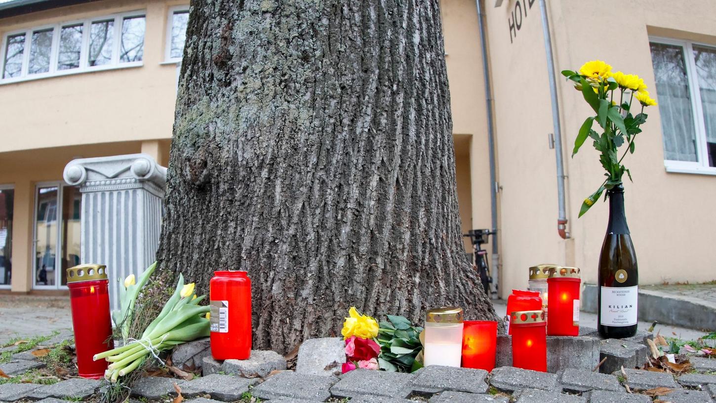 Blumen und Kerzen liegen in der Nähe der Stelle, an der einer ältere Radfahrerin gestürzt war, auf dem Boden.