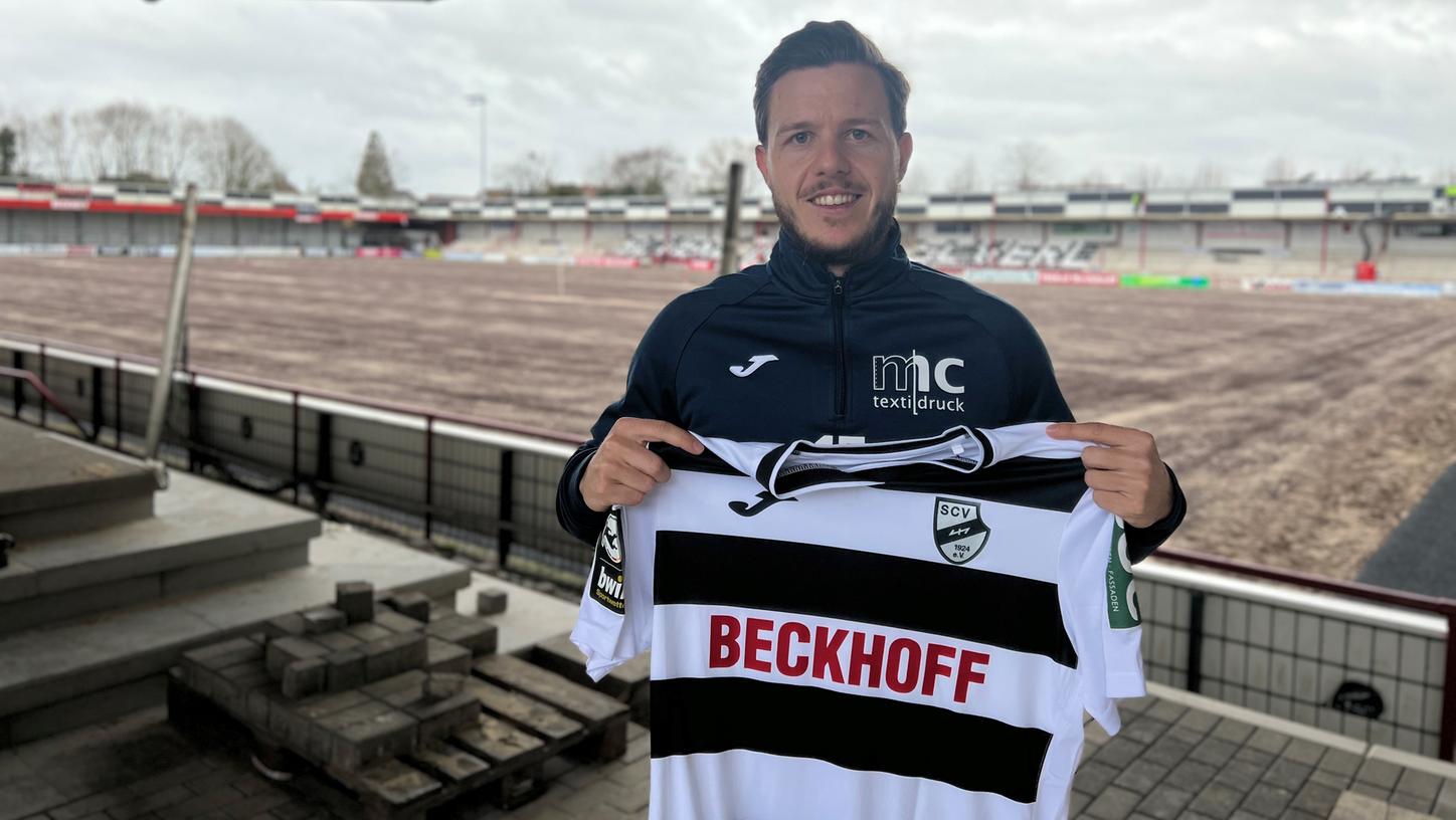 Patrick Kammerbauer mit dem Trikot seines neuen Vereins SC Verl in den Händen und mit der Stadionbaustelle im Hintergrund. Aufgrund der Maßnahmen weichen die Ostwestfalen derzeit bei den Heimspielen nach Paderborn aus. Ende März/Anfang April hofft man laut SCV-Pressesprecher Norbert Meyer auf die Rückkehr „ins Wohnzimmer“ des Vereins.  