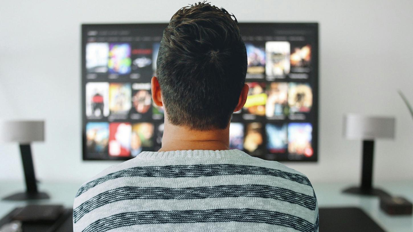 Eine Person sitzt vor dem Fernseher. Viele Streaming-Dienste erhöhen ihre Preise. 