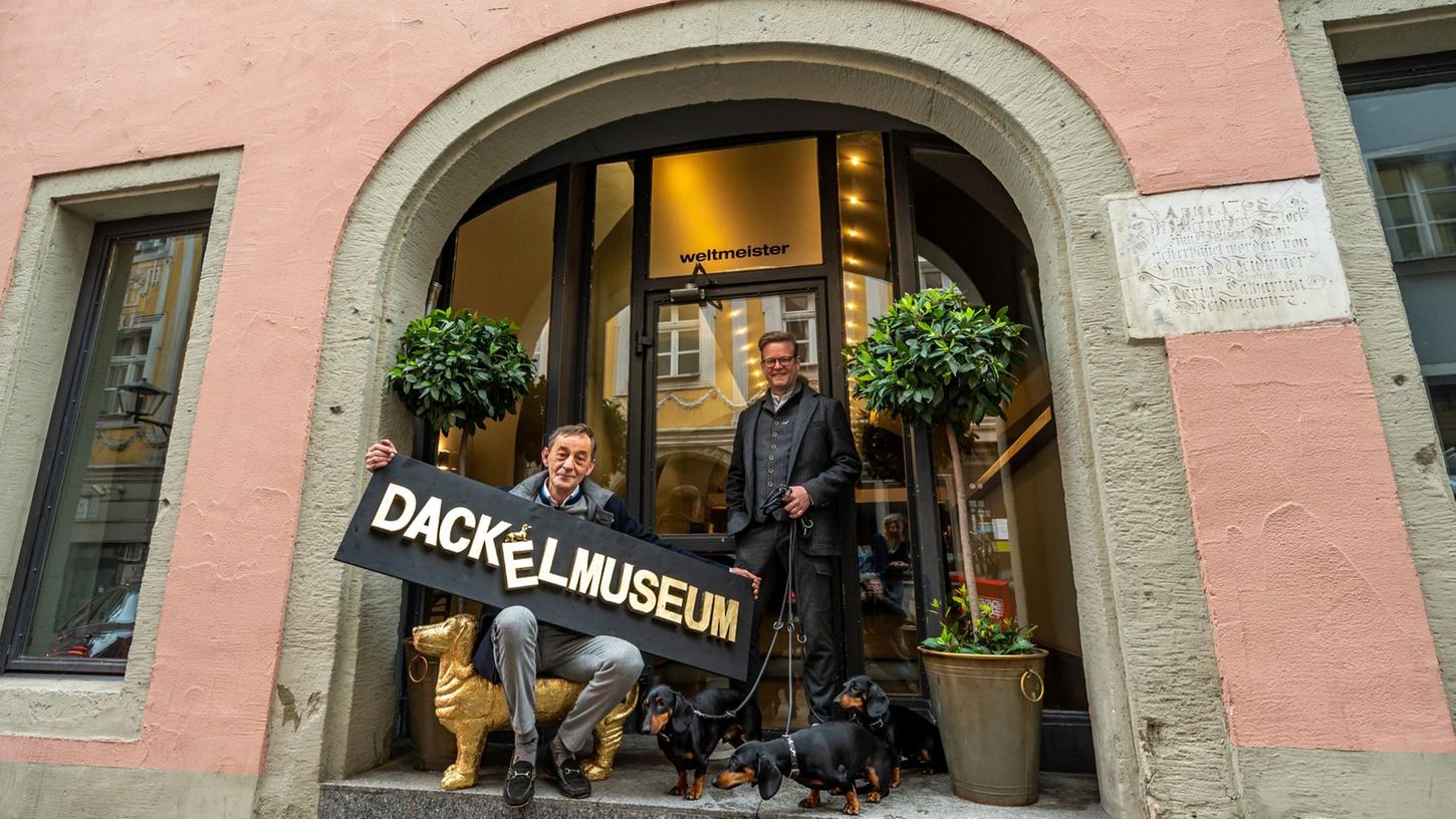 Seppi Küblbeck (l) und Oliver Storz stehen mit ihren drei Dackeln vor dem zukünftigen Dackelmuseum.