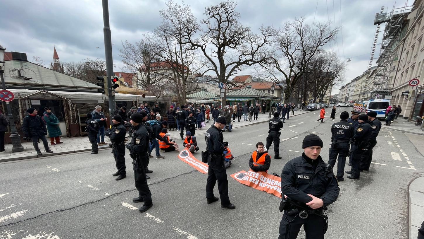 Aktivisten der "Letzten Generation" haben sich am Viktualienmarkt in München auf der Straße festgeklebt.