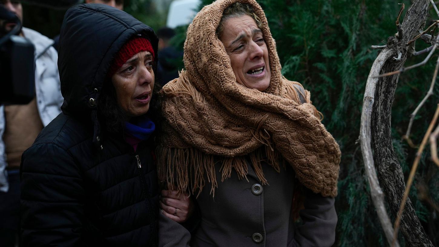 Frauen weinen, während sie zusehen, wie die Rettungskräfte in den Trümmern eines zerstörten Gebäudes in Adana nach Menschen suchen.