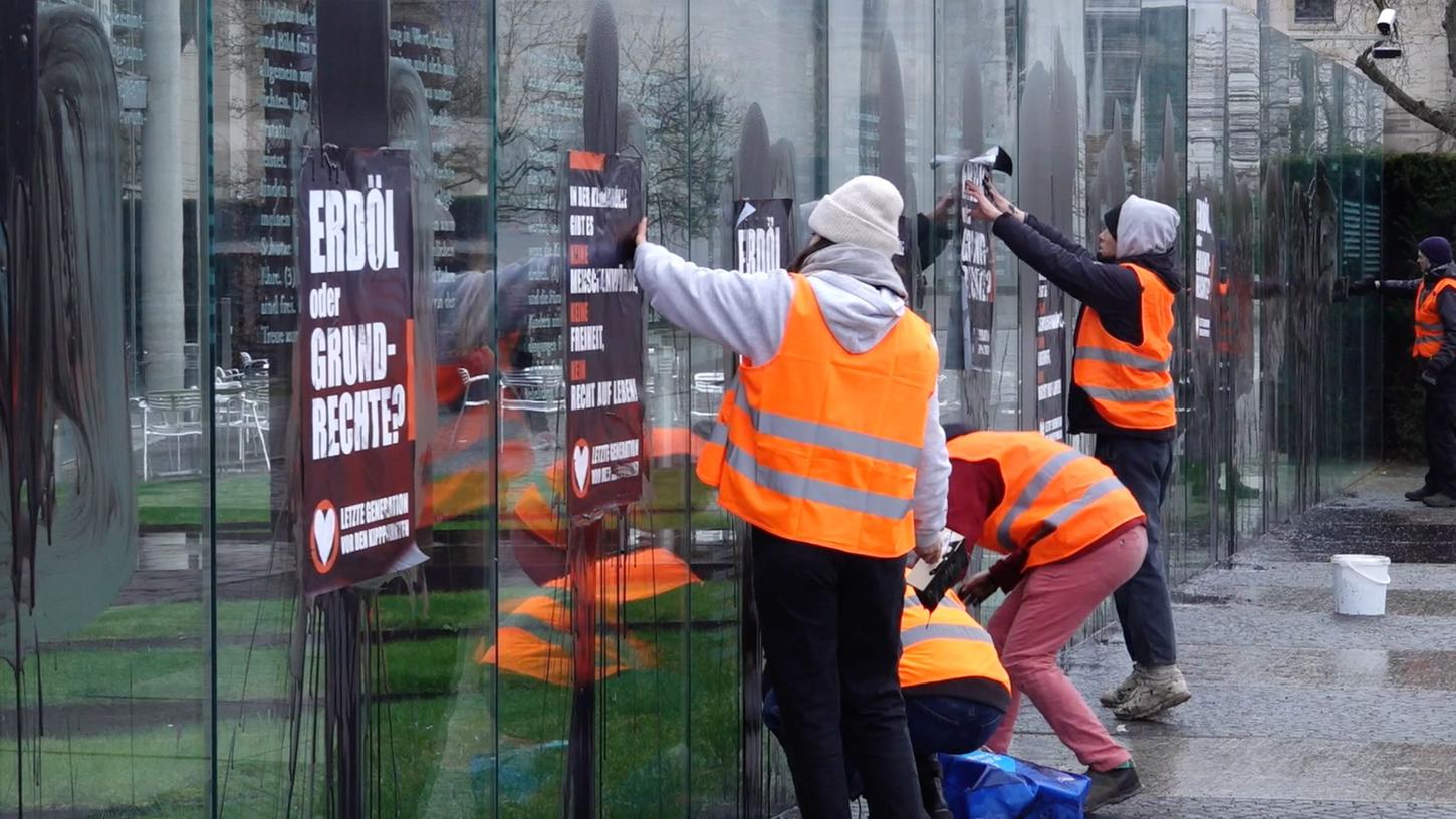 Klimaaktivisten der "Letzten Generation" beschmieren die gläserne Grundgesetz-Skulptur im Regierungsviertel und kleben Plakate darauf.