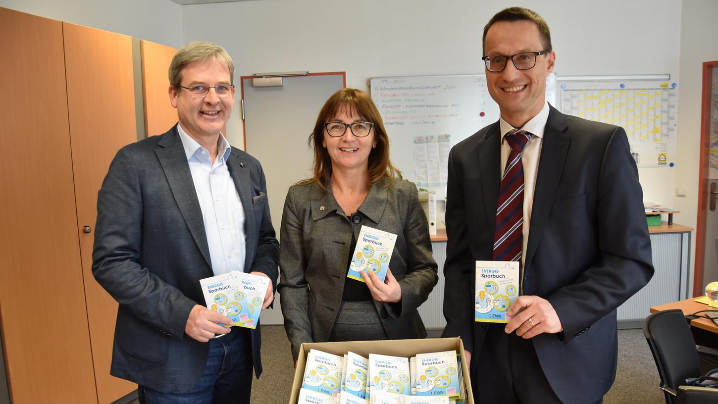 Bürgermeister Robert Ilg, Elke Kaufmann von der Diakonie Nürnberger Land und Harald Kiesl von der Hewa (von links) freuen sich über das frisch gedruckte Energiesparbuch.