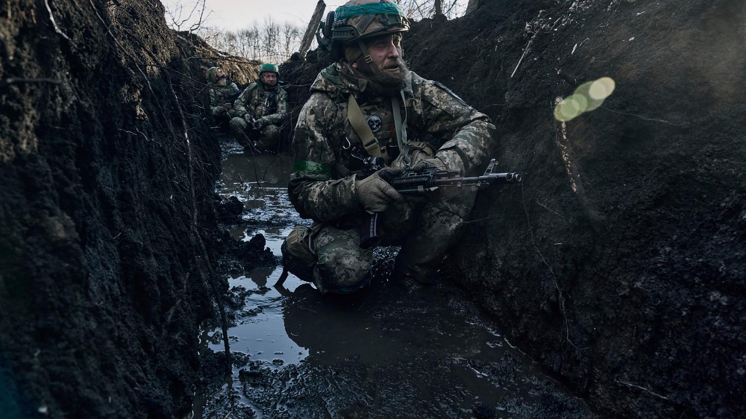 Ukrainische Soldaten hocken im Schlamm in einem Schützengraben unter russischem Beschuss an der Frontlinie in der Nähe von Bachmut. 