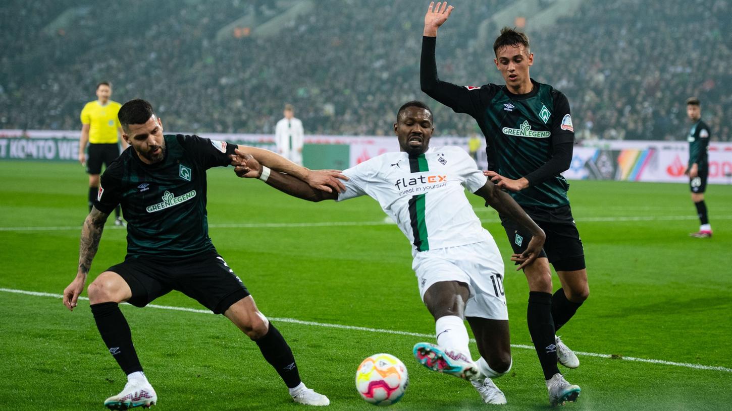 Gladbachs Marcus Thuram (M) kämpft mit Bremens Anthony Jung (l) und Fabio Chiarodia um den Ball.