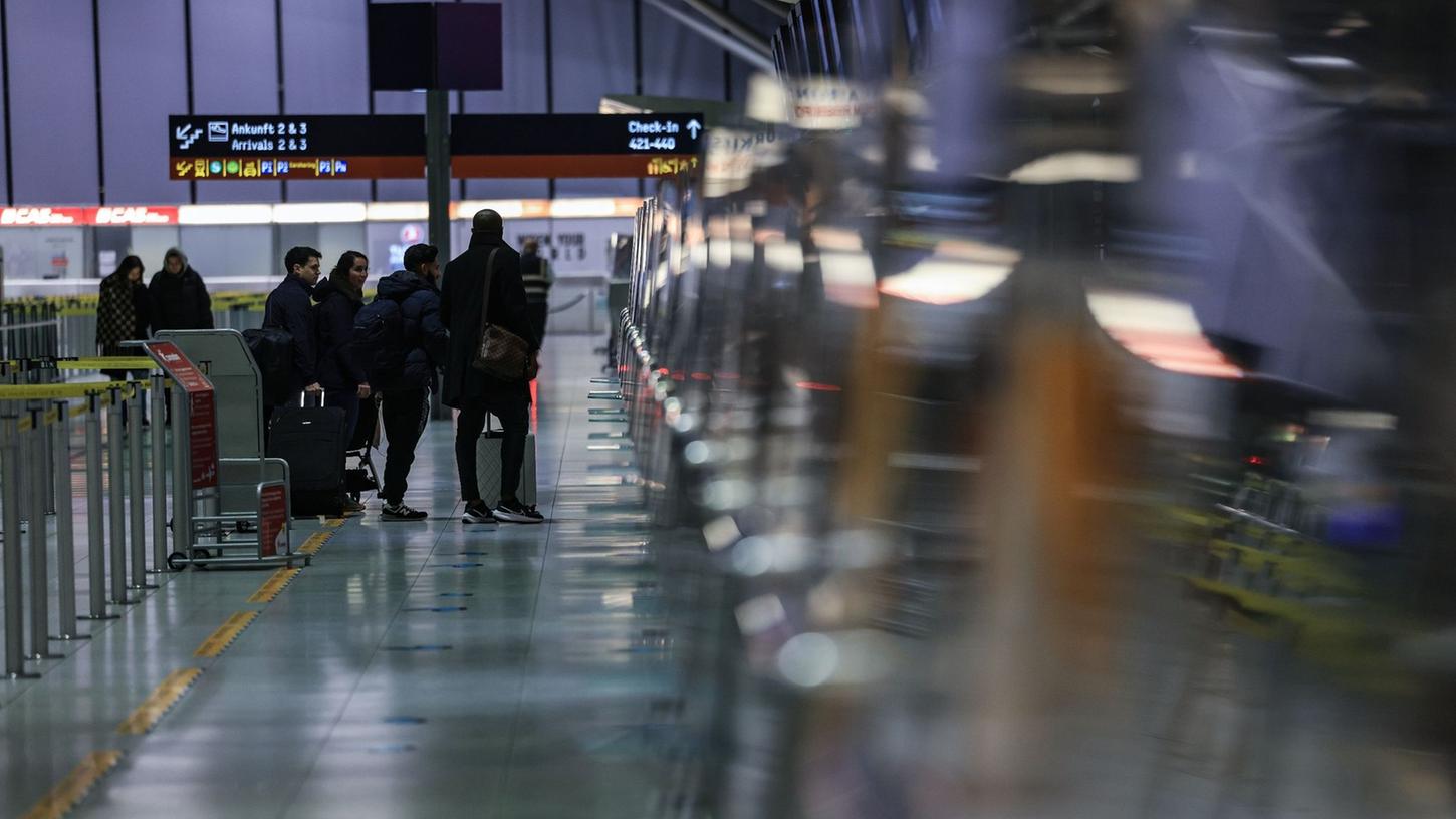 Reisende stehen am Flughafen Köln/Bonn vor einem Schalter.