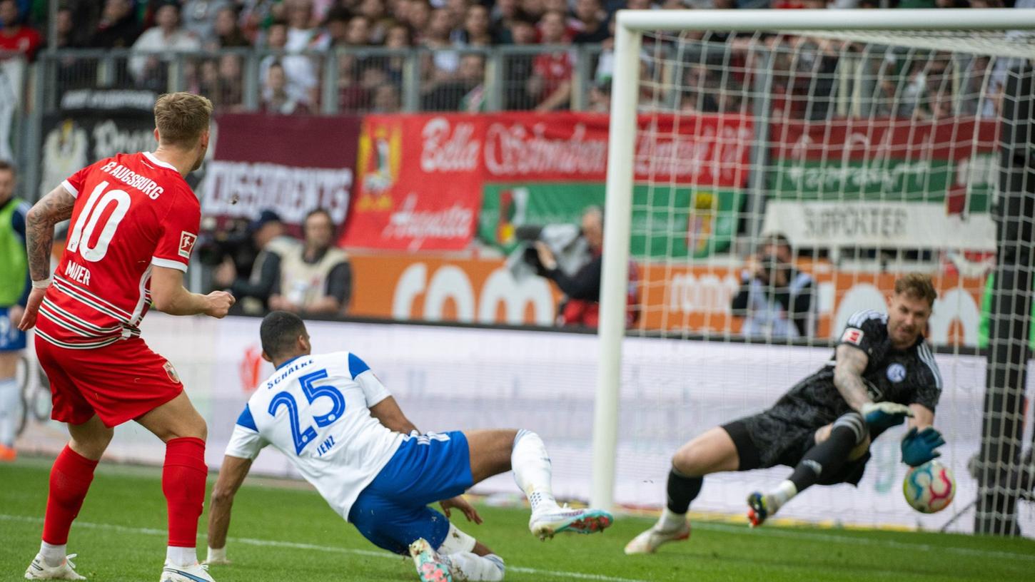 Schalkes Torwart Ralf Fährmann (r) und Moritz Jenz können das Tor von Augsburgs Arne Maier (l) nicht verhindern.