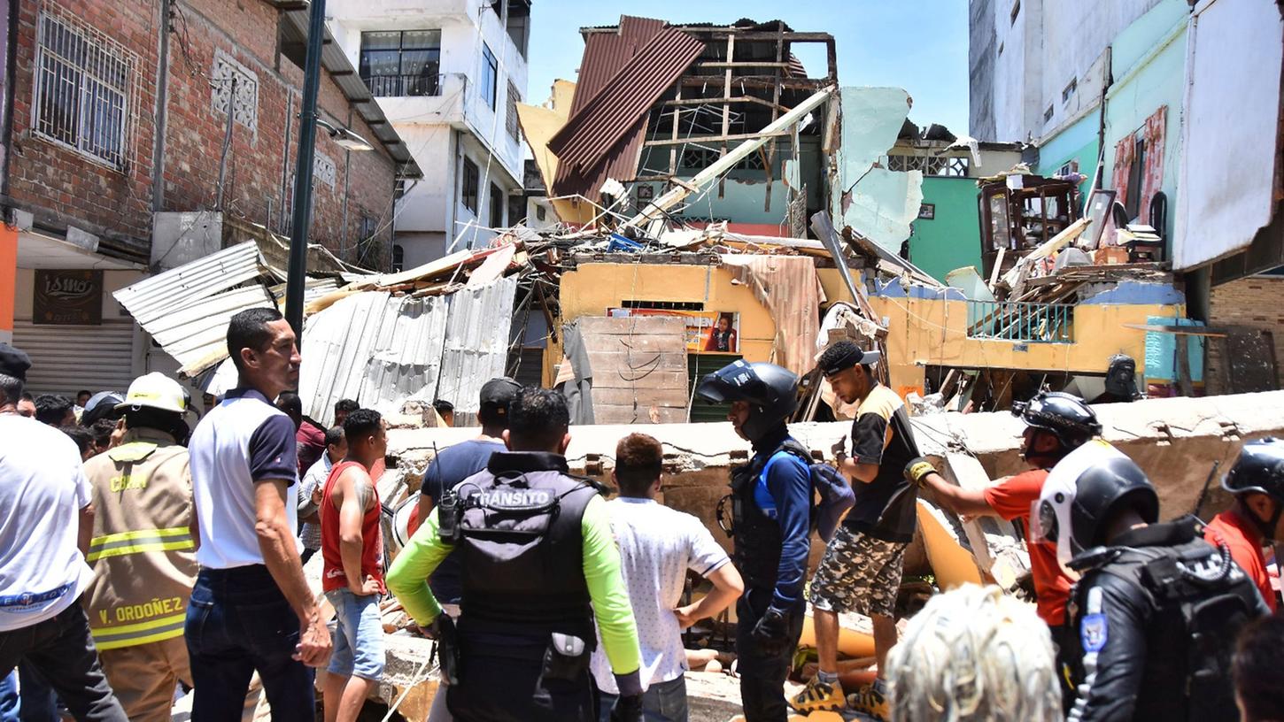 Anwohner und Rettungskräfte stehen vor zerstörten Gebäuden in Machala. Anwohner und Rettungskräfte stehen vor zerstörten Gebäuden in Machala.