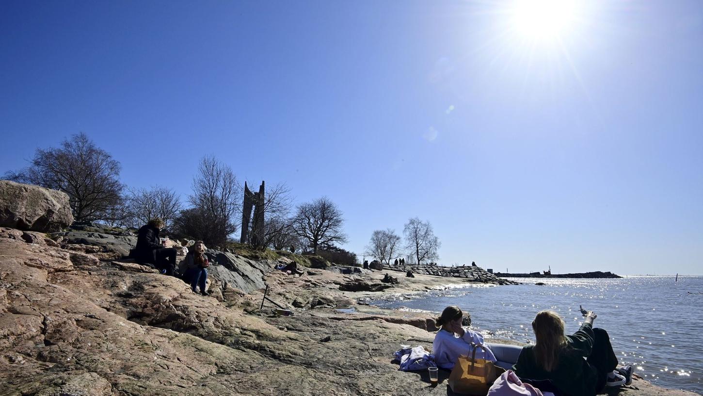 Menschen genießen in Helsinki die Frühlingssonne.