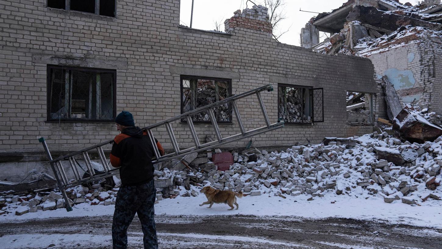 Ein Mann trägt eine Leiter durch ein zerstörtes Gebiet im ukrainischen Awdijiwka.